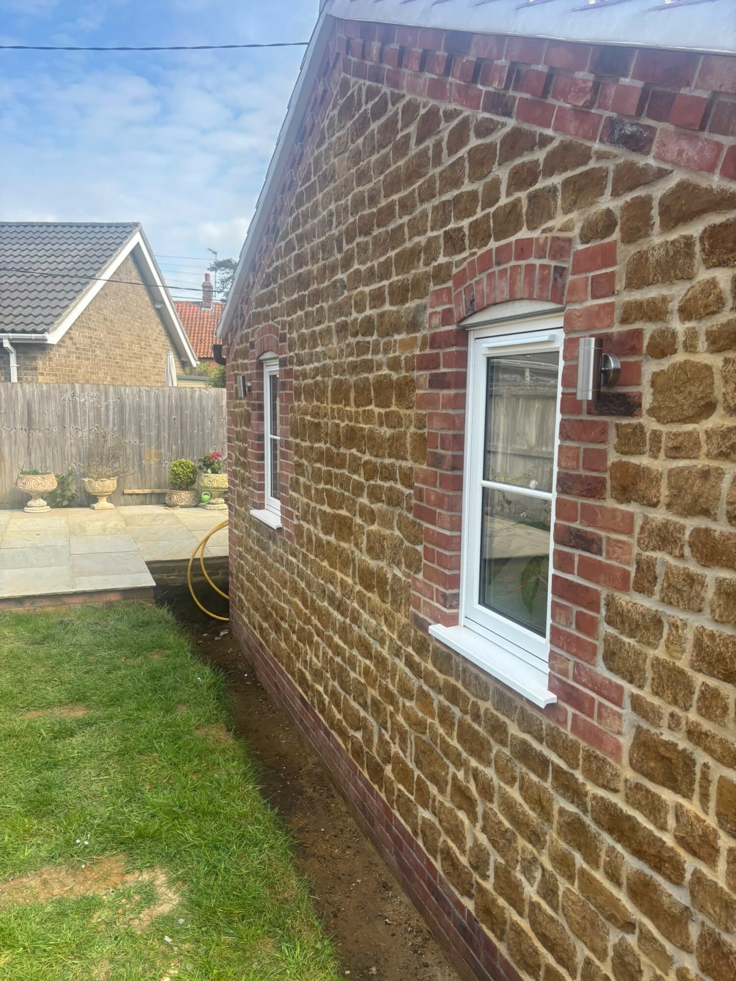 Stainless steel wall lights fitted either side of a window on a carrstone gable
