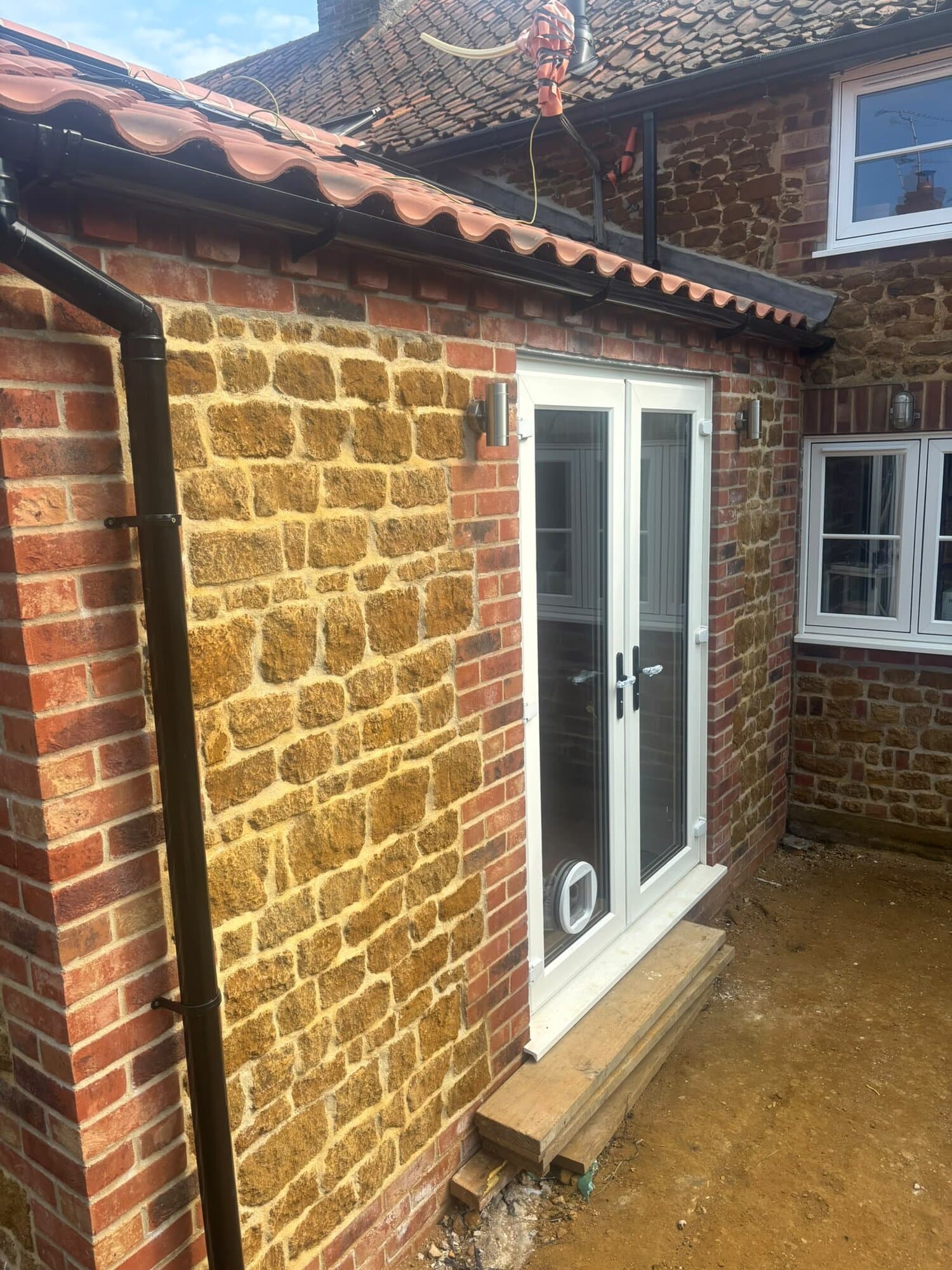 Carrstone and brick extension with new French doors and stainless steel outdoor wall lights