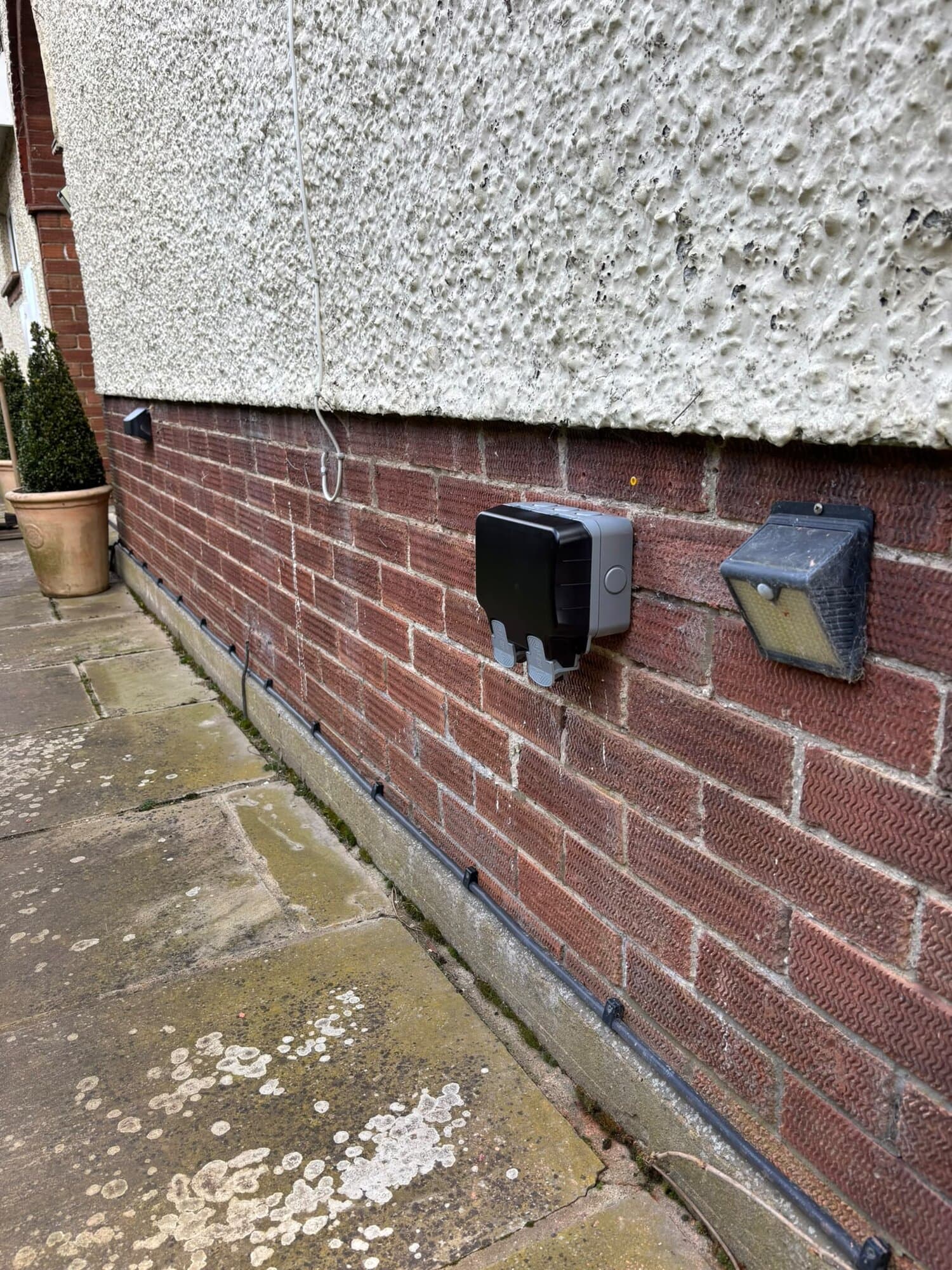 Weatherproof double socket fitted on an outside wall with tidy cable runs